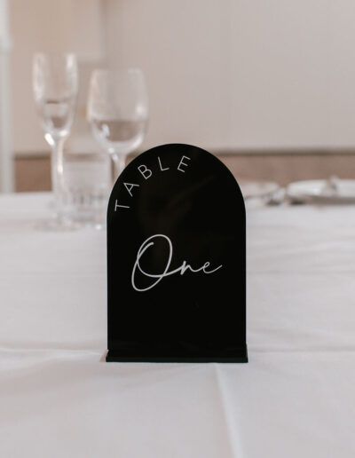 Black arched acrylic table sign with white lettering