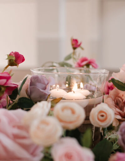 Floating candles in glass bowl among pink roses