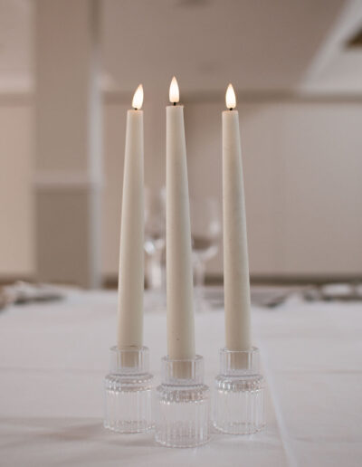 Three ivory taper candles in ribbed glass holders