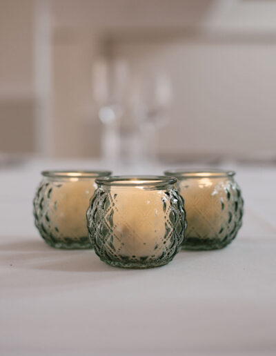 Three sage green patterned glass votives