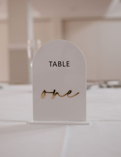 White arched table sign with gold mirrored script