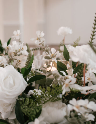 White roses and foliage around glass candle holder